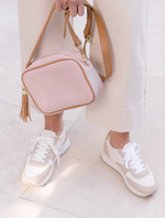 a pink vegan leather cross body bag by zjoosh with tan contrast piping and straps