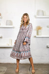a white floral bohemian midi length dress with long sleeves and contrasting border details